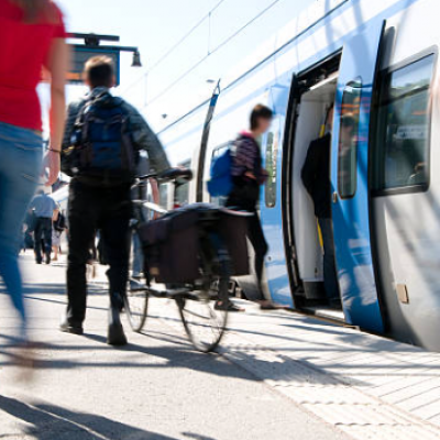 Cycliste homme de dos sur le quai d'une gare avec un train à l'arrêt